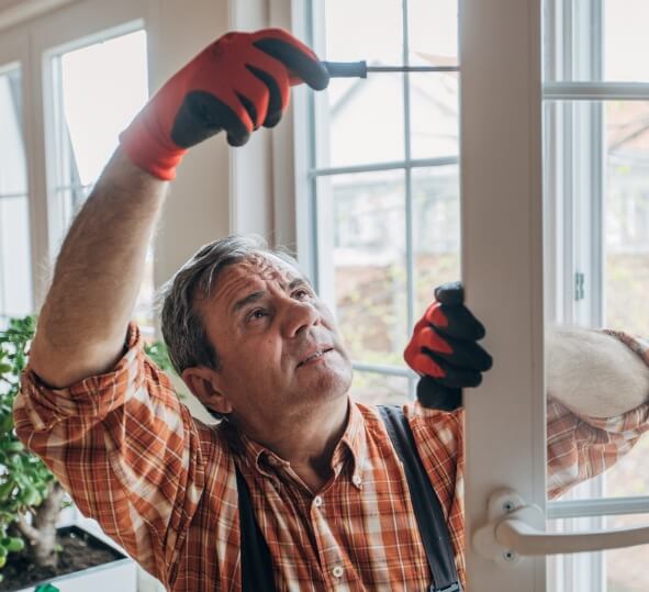 Man wearing gloves, fixing a door with a screwdriver